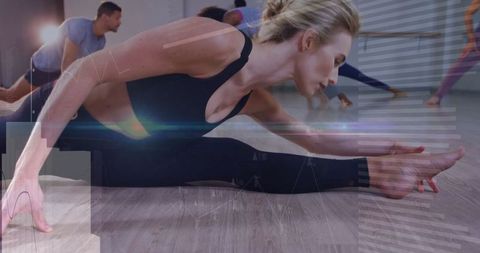 Woman in black performing stretching exercise in yoga studio