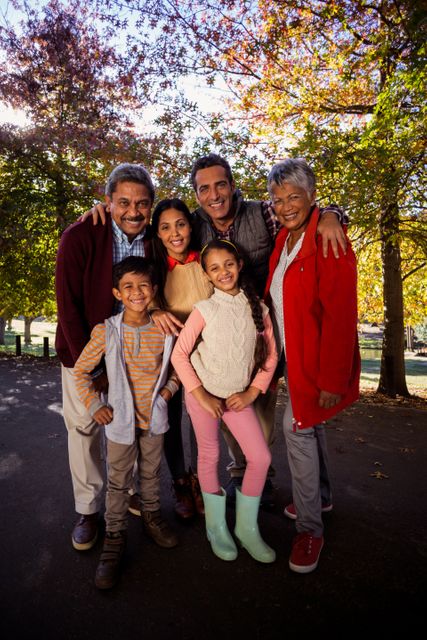Full length of smiling multi-generation family standing at park during autumn