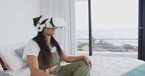 Woman Enjoying Virtual Reality by Window with Ocean View