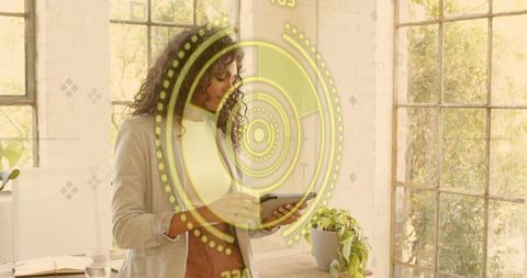 Holding tablet and reviewing augmented reality interface in sunlit modern office