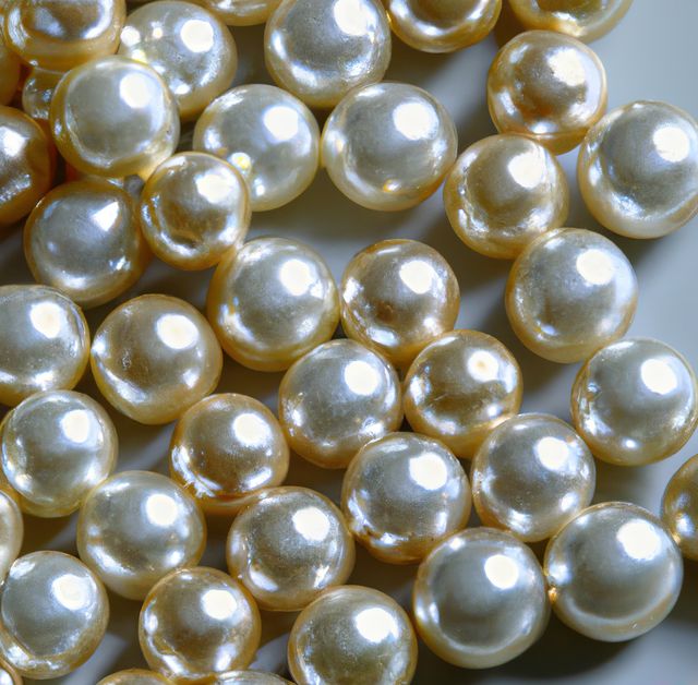 Perfect for advertisements about luxury jewelry, elegance, and beauty, this image of sparkling pearls highlights their smooth and shiny surfaces. Suitable for backgrounds in fashion blogs, jewelry stores, or design projects requiring a touch of opulence.