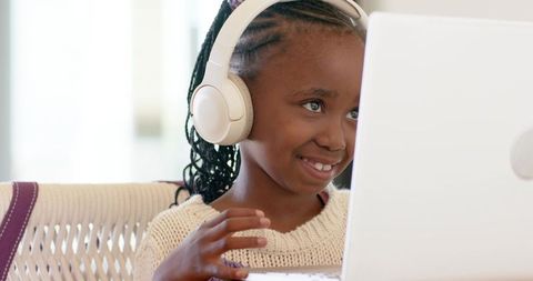 African american girl learning on laptop with headphones smiling in online study at home