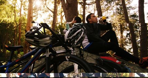 Cyclist Taking Refreshment Break in Sunlit Forest