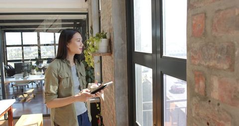 Thoughtful Businesswoman Holding Notebook in Modern Office