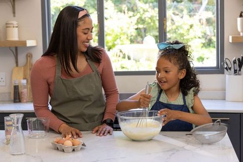 Mother and daughter whisking batter on marble countertop, sharing home baking moment