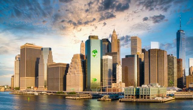 Sun sinking bathing green eco tower reflecting on waterfront skyline at golden hour