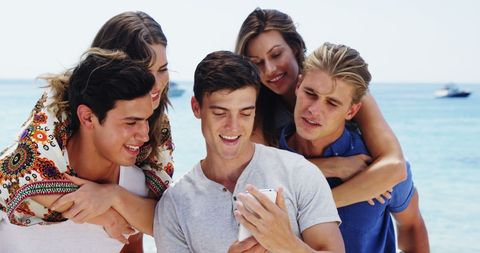 Friends Laughing and Enjoying Smartphone on Sunny Beach - Download Free Stock Images Pikwizard.com
