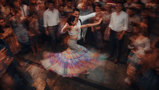 Vibrant spinning couple dancing at lively wedding reception with swirling colorful skirt