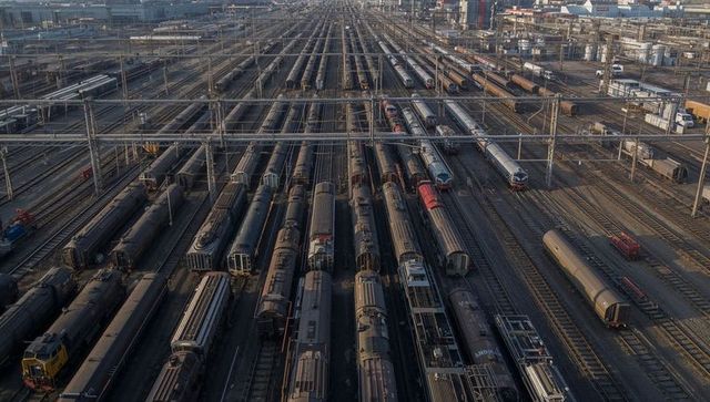 Aerial rail yard showing rows of freight trains, overhead catenary and industrial tracks