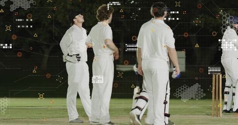 Cricket players standing under floodlights with augmented hud overlay on night pitch