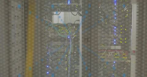 Rack-mounted servers glowing with blue leds behind perforated cabinet door in datacenter