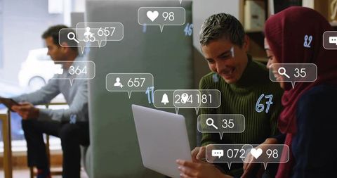 Collaborating on laptop while tracking social media engagement with floating notifications