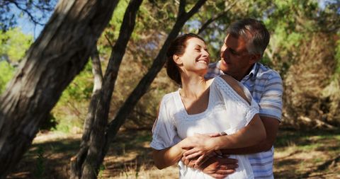 Middle-Aged Caucasian Couple Embracing Joyfully in Sunlit Forest - Download Free Stock Images Pikwizard.com