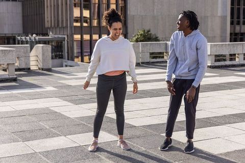 Friends laughing and talking on urban rooftop terrace in hoodies and sneakers