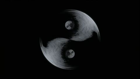 Monochrome yin-yang moons rotating over black void with cratered texture and symmetry