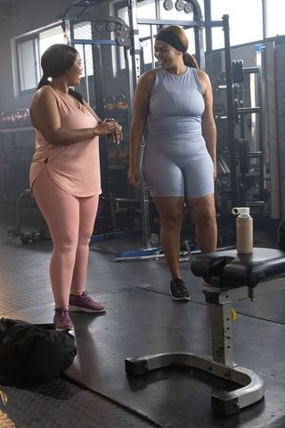 African american women talking in gym activewear, friendship and fitness motivation
