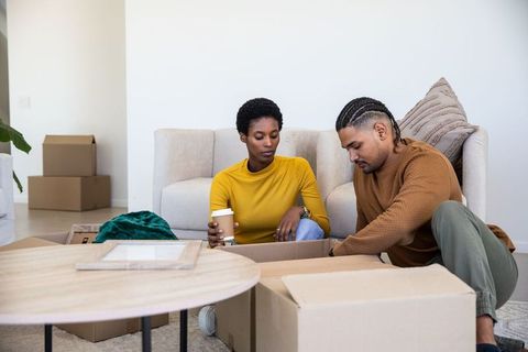 Diverse Couple Unpacking Moving Boxes Together in Cozy Living Room