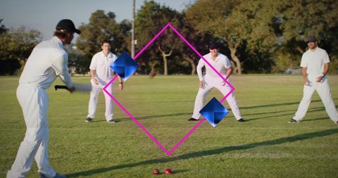 Cricket batsman swinging toward fielders on sunny green pitch with red ball action