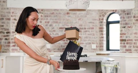 Woman preparing birthday party with cake and presents