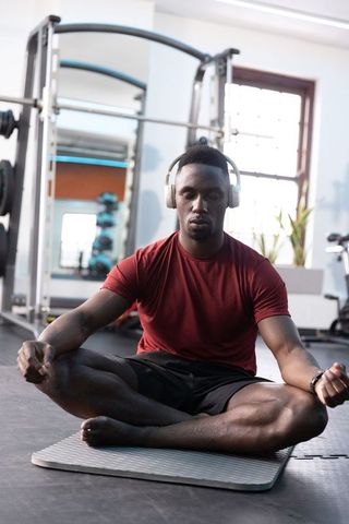 Young athlete meditating with headphones on gym mat practicing mindfulness and focus