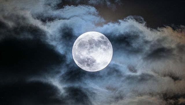Full Moon with Luminous Halo and Crater Detail Framed by Wispy Night Clouds