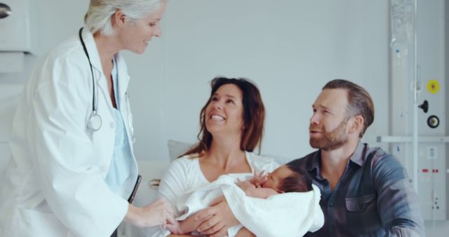 Happy parents with newborn baby talking to doctor in hospital room - Download Free Stock Images Pikwizard.com