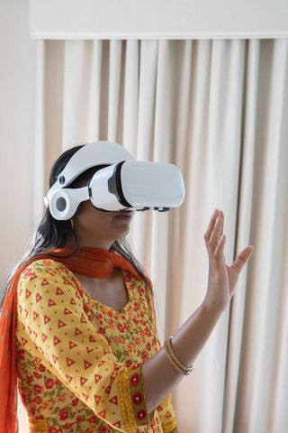 Woman engages in VR with traditional clothing at home for immersive tech experience
