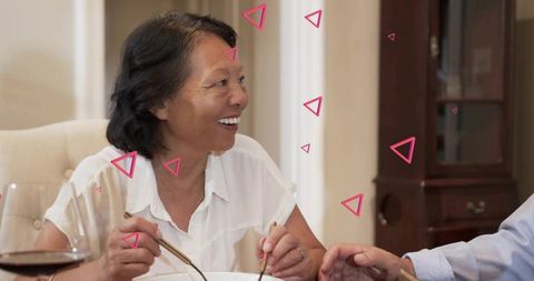 Smiling senior woman sharing family dinner with chopsticks warm cozy home moment