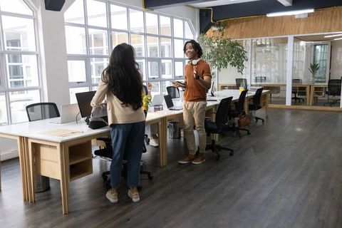 Indian woman and african american man collaborating at modern coworking office with laptops