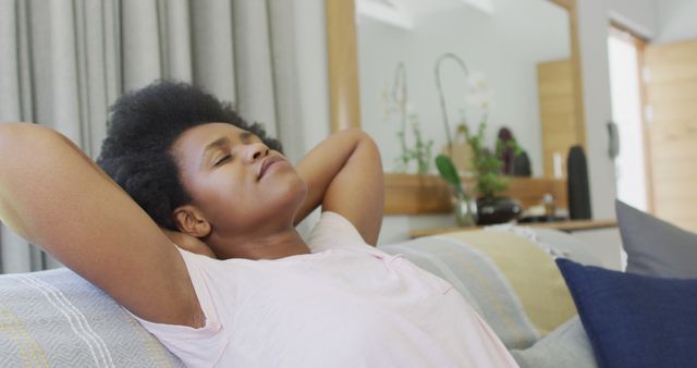 Relaxed african american woman sitting on sofa with eyes closed. domestic lifestyle, spending free time at home.
