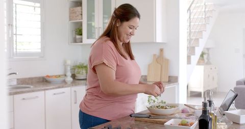 Happy Woman Cooking in Modern Kitchen with Tablet