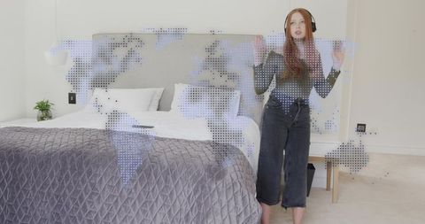 Young woman wearing headphones interacting with dotted world map in modern bedroom