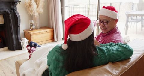 Senior Father with Adult Daughter in Santa Hats Celebrating Christmas