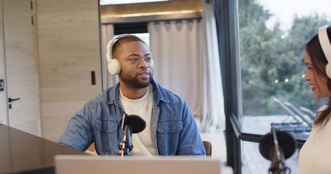 Diverse co-hosts recording conversational podcast at modern home studio with natural light