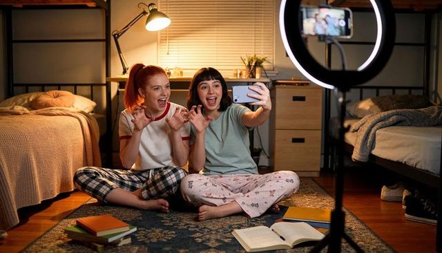 College roommates filming late-night pajama vlog with ring light and smartphone