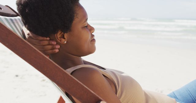 Woman relaxing on a beach lounger by the ocean. This image can be used for travel advertisements, vacation destination promotions, wellness and mindfulness promotions.