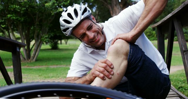 Man with bike helmet on bridge holding injured leg - Download Free Stock Images Pikwizard.com