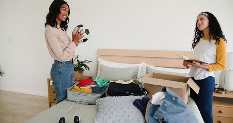 Mother and Daughter Packing for Vacation in Bedroom
