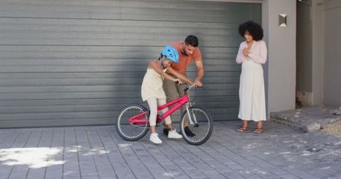 Father Teaching Daughter to Ride Bicycle in Driveway