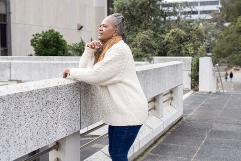 Older woman leaning on granite railing, contemplative urban terrace lifestyle portrait