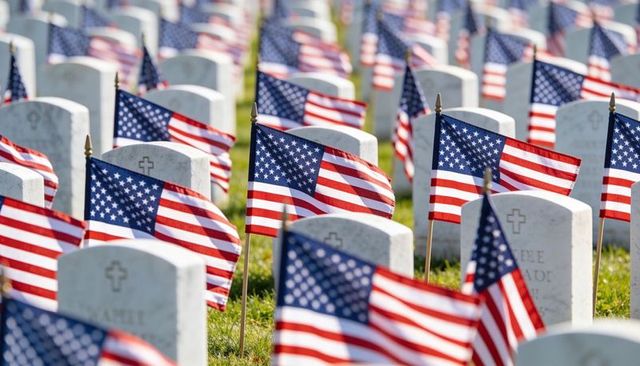 American flags lining military cemetery rows on memorial day with sunlit headstones