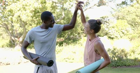 Happy Couple High-Fiving with Yoga Mats in Sunny Park
