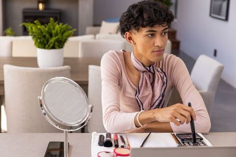 Fashionable Young Man Applying Makeup at Home with Mirror