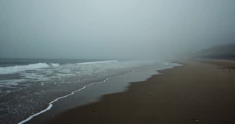 Waves Crashing in Fog on Serene Beach Shoreline