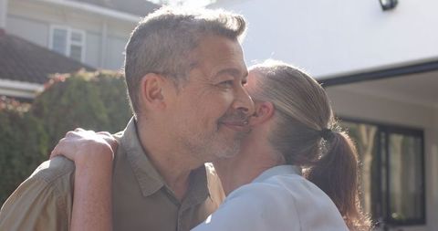 Senior couple embracing outdoors with suburban house background