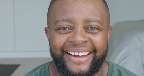 Smiling african american man wearing green t-shirt looking at camera closeup headshot