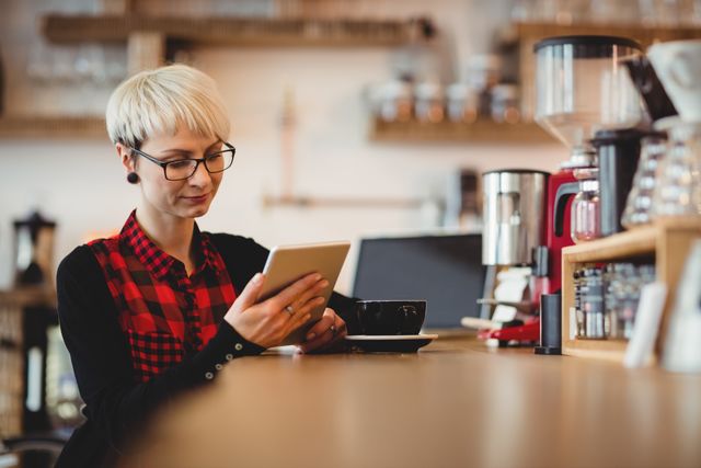 Young woman using digital tablet while having coffee at office cafeteria