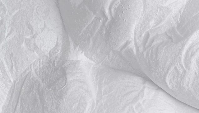 Macro crumpled white fabric texture showing soft folds, creases and minimalist pattern