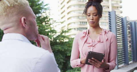 Professional Team Discussing Strategy with Tablet Outdoors