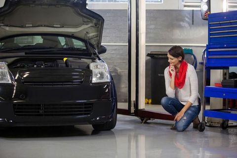 Woman Inspecting Engine in Auto Workshop with Tool Chest Nearby